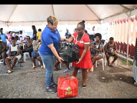 State Minister in the Ministry of Health and Wellness, Krystal Lee (left), hands over a care package to expecting mother Shanae Cooper-Robinson during a maternal health outreach at the Black River Health Centre in St Elizabeth on November 21.