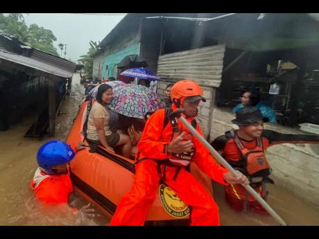 In this photo released by the Indonesian National Search and Rescue Agency (BASARNAS), rescuers on a rubber boat evacuate residents from their flooded home in North Sumatra province, Indonesia Tuesday, November 25, 2025. (BASARNAS via AP)