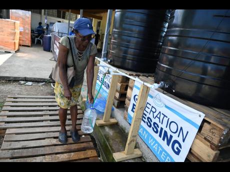 A Montego Bay resident collects water at the Operation Blessing headquarters on the Trumpet Call Ministries grounds in Montego Bay, St James.