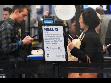 A Real ID sign is displayed as travellers wait to go through security check point at O'Hare International Airport in Chicago, May 23, 2025. (AP Photo/Nam Y. Huh, File)