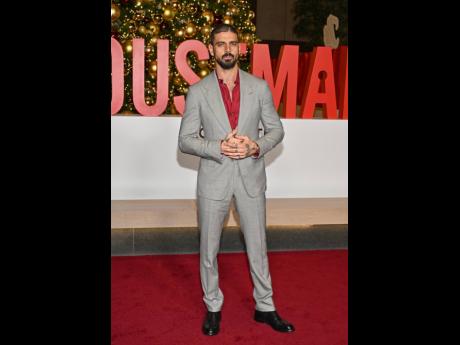 Michele Morrone cuts a sharp figure in a grey suit offset by a deep red shirt.