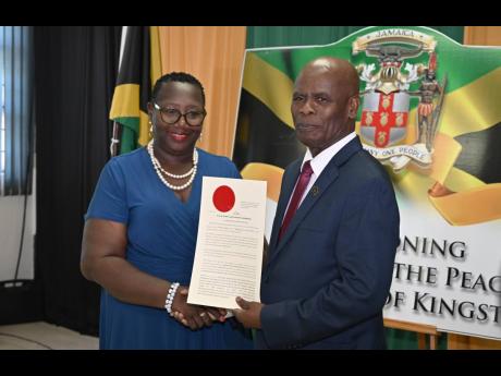 Custos of Kingston, Steadman Fuller (right) presents newly commissioned Justice of the Peace for the parish, Marlene Brooks-Sinclair, with her instrument of appointment, during a commissioning ceremony held on December 4, 2025, Kingston Bookshop, downtown