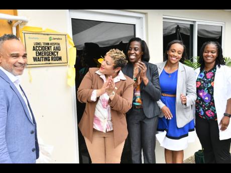 Minister of State in the Ministry of Health and Wellness, Krystal Lee (second left), applauds as she views the plaque dedicating the newly renovated Accident and Emergency Waiting Area at the Lionel Town Hospital in Clarendon, during the official opening o