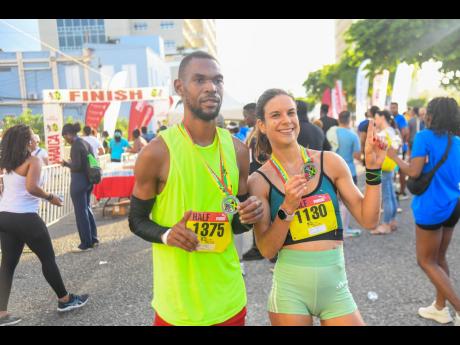 Garfield Gordon (left) and Cecile Heinrich pose with their medals after topping the men’s and women’s half marathon event, respectively, at the 2026 Reggae Marathon in downtown Kingston yesterday. 