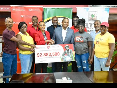 Minister of Agriculture, Fisheries and Mining, Floyd Green (5th right), shakes hands with the GraceKennedy Group's Head of General Insurance, Tammara Glaves-Hucey (4th left), during the recent symbolic handover of a $2.88 million insurance payout under the