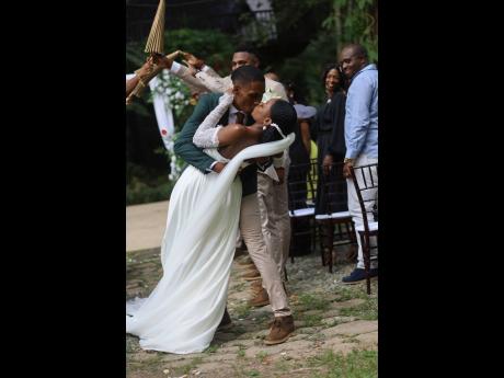 Just married! A joyful moment captured in the aisle as the wedding party celebrates the passionate kiss between the newly-weds.