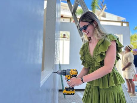 Credit: Ashley Anguin/Photographer Monica Biazzi, a tourist at the S Hotel Montego Bay, drills a section of one of the 60 homes built by S Hotel Montego in 30 days for families displaced by Hurricane Melissa at S Hotel Montego.