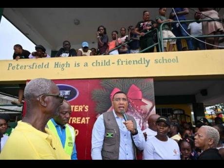 Prime Minister Dr Andrew Holness (centre) addressing residents at the Petersfield High School in Westmoreland on Saturday, December 13, 2025 during the Prime Minister’s Christmas Treat. Also participating were (from left) Minister of Local Government and
