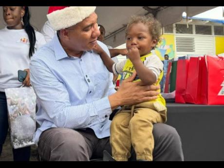 Prime Minister Dr Andrew Holness interacts with a young child at a Christmas kiddies treat at the Middle Quarters Primary and Infant School in St Elizabeth on December 13, 2025.