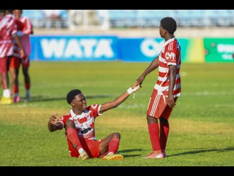 Credit: Matthew McKoy Glenmuir High School’s Tequaianne Allen is helped up by teammate Conroy Nicely during their ISSA daCosta Cup semi-final game against Dinthill Technical High School at Sabina Park yesterday. Glenmuir won 2-1.