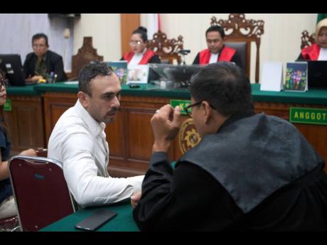 Australian national Lamar Ahchee, left, who is on trial on accusation of attempting to smuggle cocaine into Indonesia, talks to his lawyer during his sentencing hearing at the district court in Denpasar, Bali, Indonesia on December 18, 2025. 