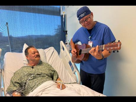 Nurse Rod Salaysay plays guitar for patient Richard Hoang in the recovery unit of UC San Diego Health in San Diego, California, on September 30, 2025. 