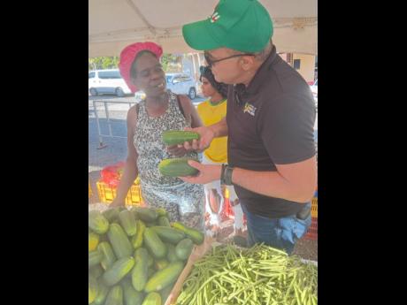 Dr Christopher Tufton, Member of Parliament for St Catherine West Central, speaks with vendor Annmarie Reid about cucumbers during the Green Acres Farmer’s Market in St Catherine on December 22, 2025. 
