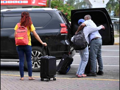 Credit: Ricardo Makyn/Chief Photo Editor A traveller is greeted with a warm hug on arrival at the Norman Manley International Airport on Monday.