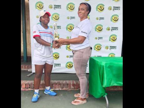 Credit: Contributed Jade Fearon (left) collects one of her trophies from Ann Marie Maxwell, All Jamaica Tennis administrator, during the All Jamaica Tennis Championship held at the Eric Bell National Centre on Saturday, December 20, 2025. Fearon won the under-16 and under-18