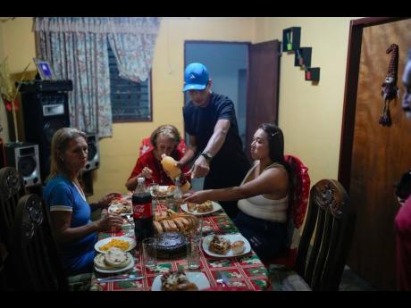 Mariela Gómez (right) and her partner Abraham Castro, a migrant couple, sit for Christmas dinner at Castro’s parents’ home in Maracay, Venezuela.