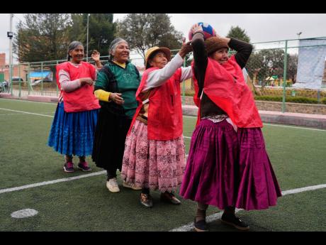 An Aymara grandmother passes the ball during a warm up before the start of a handball match in El Alto, Bolivia.