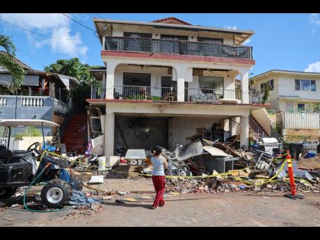 Credit: Marco Garcia A woman stands in front of the home where a New Year's Eve firework explosion killed and injured people, January 1, 2025, in Honolulu. (AP Photo/Marco Garcia, File)