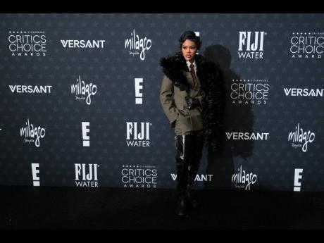 Teyana Taylor wears a Saint Laurent suit and thigh-high boots, paired with a dramatic stole, and Tiffany & Co jewellery. 