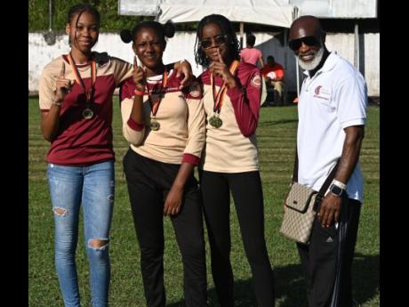 Credit: Ashley Anguin Comets Club International President Michael Campbell (right) poses with members of the Herbert Morrison Technical High School team after presenting them with medals at the second staging of the Run for the Republic development meet at the school on Saturda