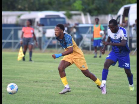 Racing United’s Kadean Young runs away from Mount Pleasant Academy’s Clifford Thomas during their Jamaica Premier League game at the Drax Hall Sports Complex yesterday.