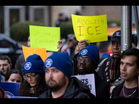People raise signs in support of immigrants during a news conference outside Greater New York Federal Building, Tuesday, January 13, 2026, in New York. (AP Photo/Yuki Iwamura)