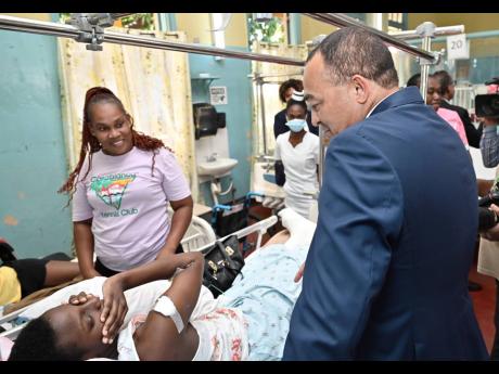 Credit: Rudolph Brown/Photographer Dr Christopher Tufton, minister of health & wellness, speaks with Oshean Noble (left) and her daughter, Tiffany Campbell, during a tour of Ward 1 at the launch of the Family Caregivers Pilot Programme at the Bustamante Hospital for Children on Arthur Wint