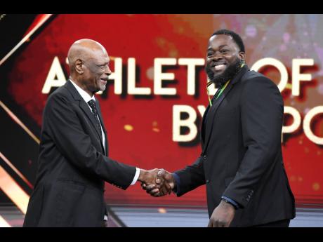 Chad Wright, 2025 Weightlifting Athlete of the Year (right), collects his award at the RJRGLEANER National Sports Award at TVJ Studios on Sunday from George Campbell, General Manager, Coldfield Manufacturing/Pure Country.