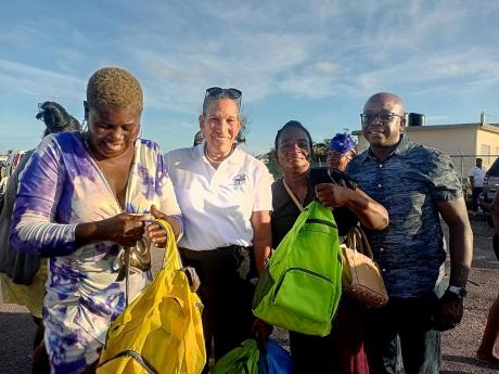 Colleen Wint-Bind (second left), project coordinator at the Violence Prevention Alliance (VPA), presents care packages to parents at Rocky Point in Clarendon at a community outreach activity organised by the VPA. Sharing in the moment is Pearnel Charles Jr