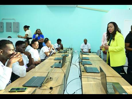 Permanent Secretary in the Ministry of Education, Skills, Youth and Information, Dr Kasan Troupe (right), engages with Bustamante High School students, during the handover of renovated and expanded information communications technology facilities at the in