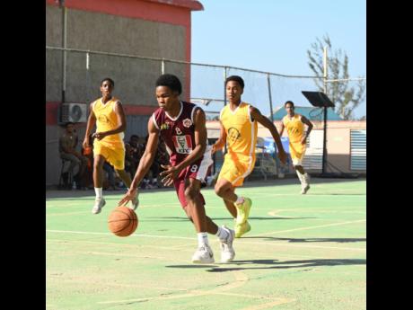 Herbert Morrison Technical High School’s Ryan Jurdine (front) dribbles away from Garvey Maceo High School’s Nicade Bachan (right) during their ISSA Schoolboys Rural Basketball quarterfinal match at the Herbert Morrison court yesterday.