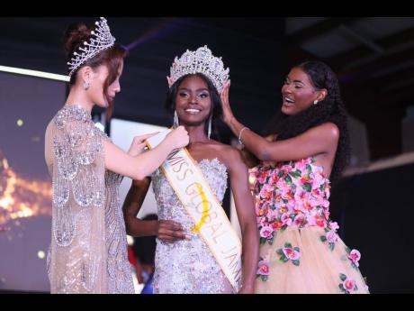 Former Miss Global Jamaica Keri-Ann Greenwood (right) passes the crown to Miss Global Jamaica 2026 Deidrian Downer (centre) at the Douglas Orane Auditorium at the Wolmers Boys’ School on Sunday morning. Fixing her sash is Miss Global 2025 Nhu Van.