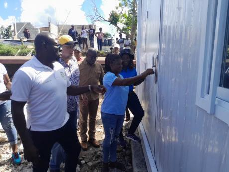 Credit: Bryan Miller photo Theresa Weddeburn joyfully turns the key to open her new home, while enjoying the moment with her are (from left) Hilroy McFarlane, managing director of C M Recycling (the donor agency of the container House); Opposition Leader Mark Golding; Mayor of Lucea