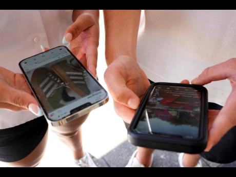 Young people use their phones to view social media in Sydney, November 8, 2024. (AP Photo/Rick Rycroft, File)