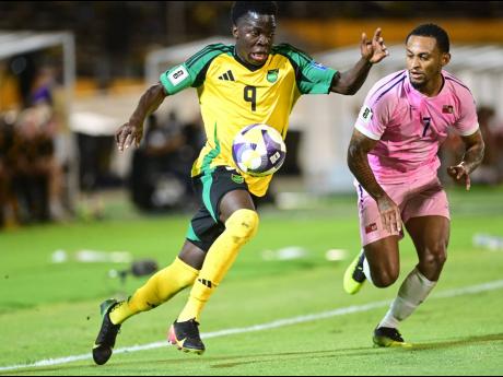 Credit: Gladston Taylor Jamaica's Kaheim Dixon (left) powers past LeJuan Simmons of Bermuda during a Concacaf Group B World Cup Qualifying match at the National Stadium.