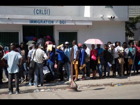 
In this 2023 photo people line up outside an immigration office as they wait their turns to apply for a passport, in Port-au-Prince, Haiti.