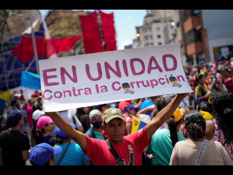 Credit: Matias Delacroix A government supporter holds a sign with a message that reads in Spanish: "In unity against corruption", during a rally against corruption, in Caracas, Venezuela, Saturday, March 25, 2023. (AP Photo/Matias Delacroix, File)