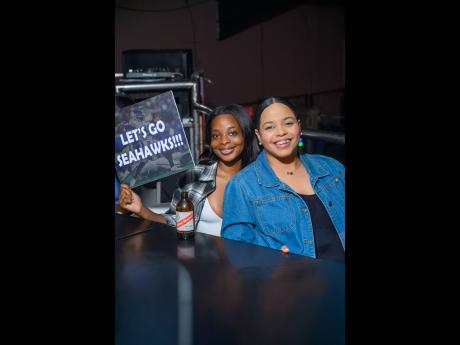 Cheering in support are Hanna Turner (left), Red Stripe junior brand manager, and Amoye Phillpotts-Brown, Red Stripe brand manager, as they show their support for the Seahawks.