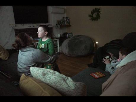 Credit: (AP Photo/Shelby Lum) Ronan Murphy snuggles with his mom, Andrea, while looking at the snow falling outside his home while brother, Connor sits nearby in Ayer, Massachusetts, USA, on January 17, 2026.
