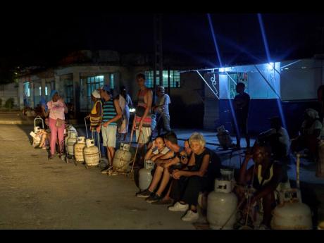 People wait to refill their cooking gas canisters in Alamar, Havana province, Cuba, late on Saturday, May 31, 2025. 