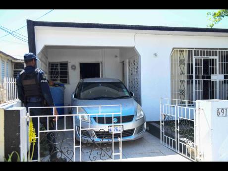 The police inspect a house on Marlin Way in Braeton, Portmore, in St Catherine yesterday where a woman and her daughter were reportedly attacked by a man believed to be of unsound mind. 