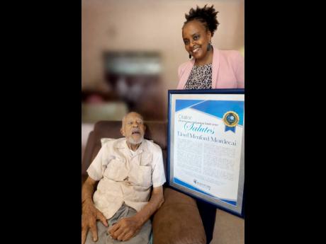 Camille Archibald, business development manager of JPS & Partners Co-op Credit Union, presents a citation to Lloyd Menford Mordecai, whose early efforts helped lay the foundation for the strong credit union we know today.