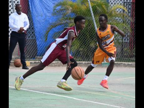 Herbert Morrison Technical High’s Michael Johnson (left) dribbles past  Manchester High’s Waine Green Jr during game one of their ISSA Rural Schoolboys Under-16 Basketball finals at Herbert Morrison’s court on Monday, March 2, 2026.