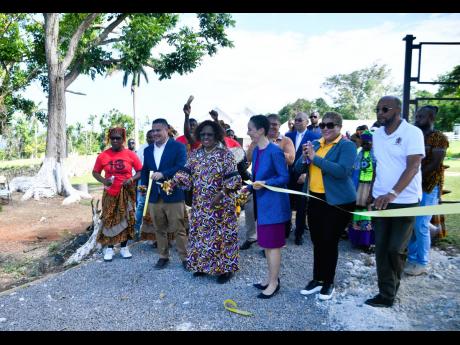 Credit: Contributed Minister of Culture, Gender, Entertainment and Sport, Olivia Grange (third left), cuts the ribbon on Friday to officially open two African-style houses constructed by the Ghana Army Engineer Reconstruction Team at Seville Heritage Park in St Ann. She is jo