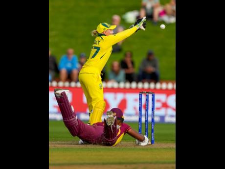 Alyssa Healy of Australia (top) takes a return throw as Hayley Matthews of the West Indies slides to make her ground during their Women’s Cricket World Cup semi-final match in Wellington, New Zealand, on March 30, 2022.