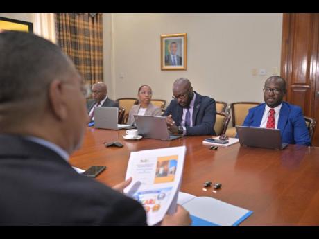 Prime Minister, Dr Andrew Holness (left), listens to Executive Director of the National Identification and Registration Authority, Dr Warren Vernon (right), during a recent meeting at the Office of the Prime Minister.