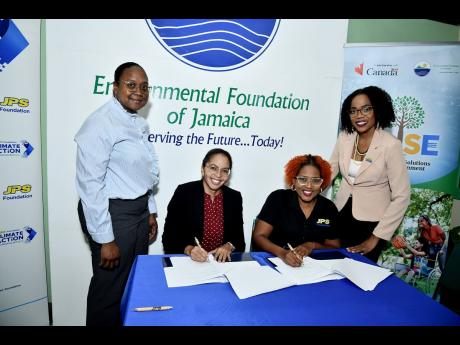 EFJ boss, Nicole Adamson (seated left) and JPS Foundation Head, Sophia Lewis (seated right) sign the MOU while Joni Jackson (left), project manager for the J-USE project, and Audrey Williams, media and public relations manager at JPS, witness the signing.