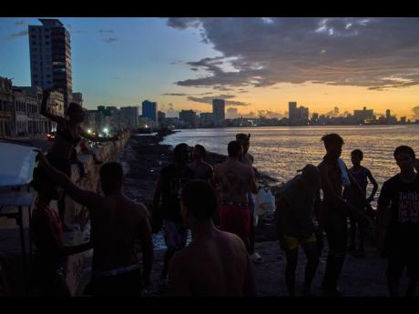 People watch the sunset from the Malecón during a blackout in Havana, Monday, March 16, 2026. 