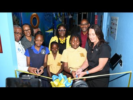 Executive Director of the Sandals Foundation, Heidi Clarke (right), assists students of Waltham Abbey Primary and Infant School and Discovery Bay Primary and Infant School in St Ann as they cut the ribbon to mark the official launch of the Immersive Marine