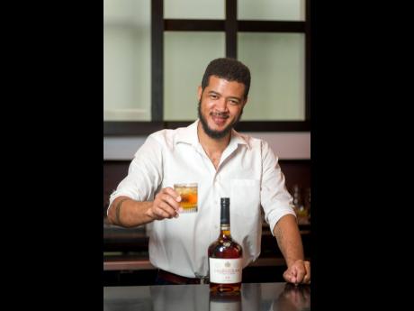 Mixologist Sheldon Spencer holding a glass of Courvoisier with ginger ale.